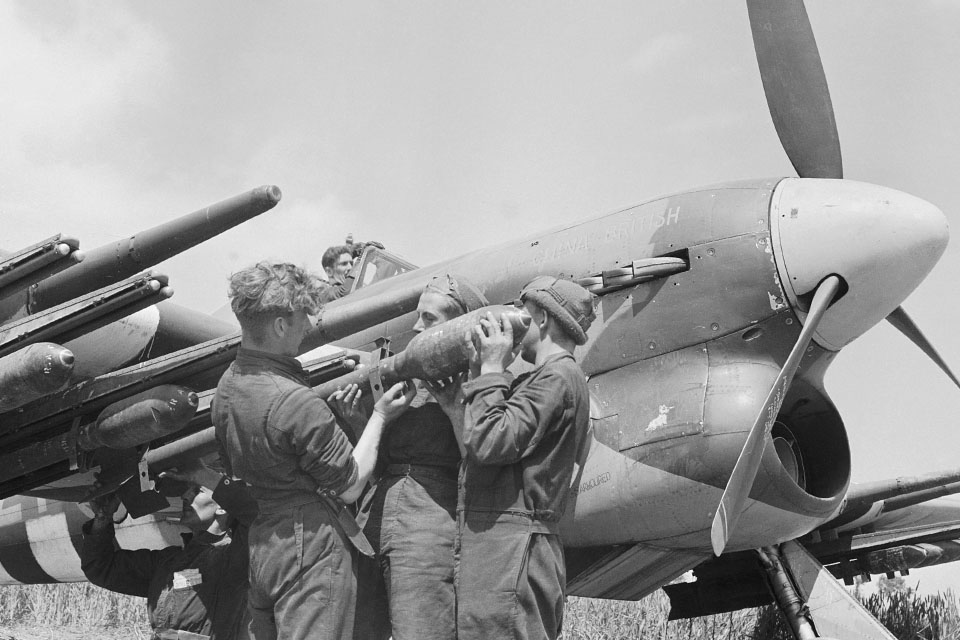 Armorers install 3-inch rockets on a No. 247 Squadron Typhoon Mark IB at Bazenville, France. (IWM CL157)